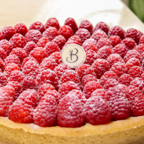 Raspberry tart with a decorative monogram on top manufacture and designed by Bake N More