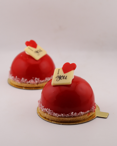 Two red dome-shaped cakes with 'I love you' tags on a light gray background